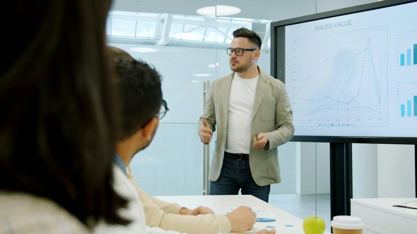Man presenting business data on a large screen to colleagues.